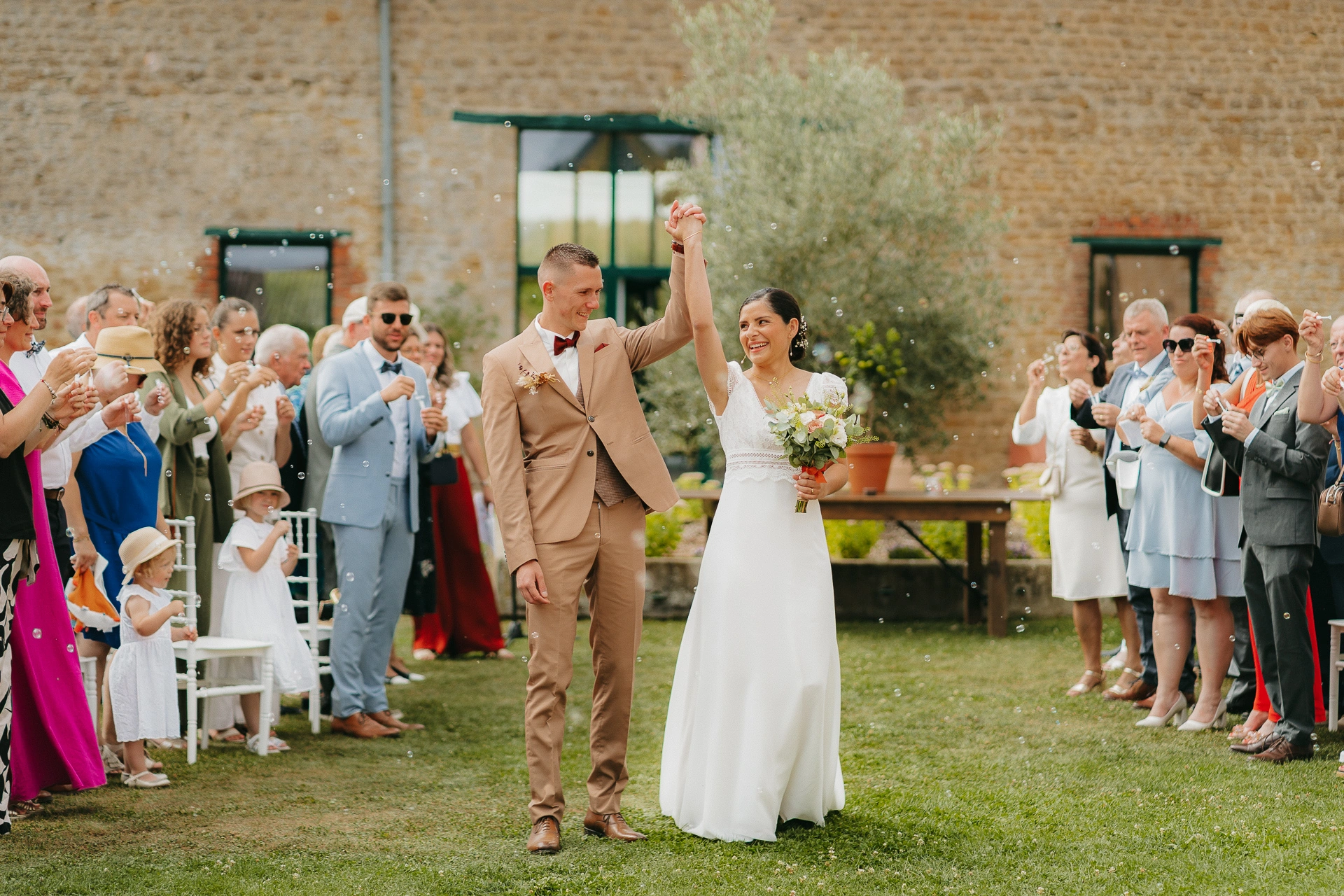Couple les bras levés, entouré de leurs invités, en plein bonheur